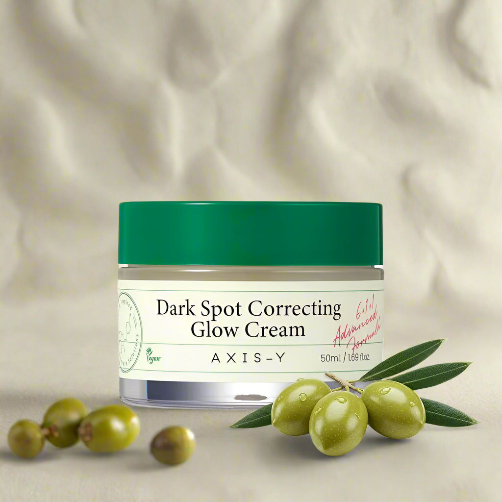Axis-Y Dark Spot Correcting Glow Cream jar with green cap and olive extract illustration.