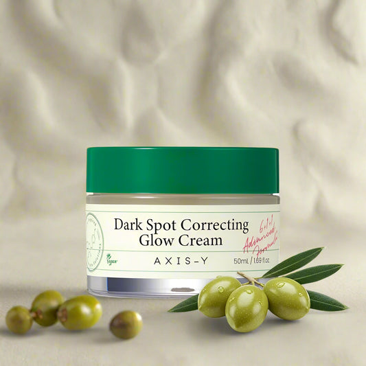 Axis-Y Dark Spot Correcting Glow Cream jar with green cap and olive extract illustration.